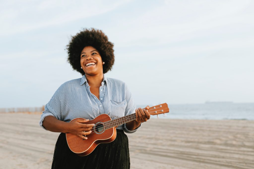 Happy woman playing a ukelele on a beach